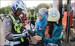  ?? DRIAN BINTANG/JAWA POS ?? TEGAS: Aiptu Siswanto (kiri) menindak pengendara yang tidak memakai helm.