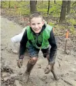  ??  ?? Ethan Morgan is all smiles as he finishes crawling under an obstacle through the mud at the fifth annual Pelham Mudfest Challenge on Saturday.