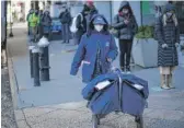  ?? KENA BETANCUR/ AFP VIA GETTY IMAGES ?? A Postal Service worker pushes a cart with deliveries through midtown New York on Wednesday.