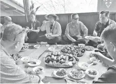  ??  ?? Christina (third from right), flanked by Peter and Ismaily, sampling Murut delicacies at Rumah Lansaran.