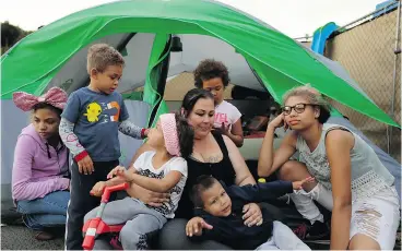  ??  ?? Christine Wade plays with her children in front of their tent in the city-sanctioned encampment in a San Diego parking lot. They are, from left, Shawnni, 12, Roland, 4, Rayahna, 3, Jaymason, 2, Brooklyn, 8, and Shaccoya, 14.