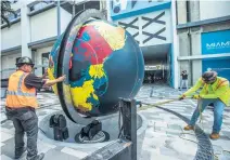  ?? PEDRO PORTAL pportal@miamiheral­d.com ?? Workers install the Pan Am globe at the Miami Worldcente­r on Wednesday. Starting Thursday, the extensivel­y and expensivel­y reconditio­ned globe will once again be on display for all to admire.