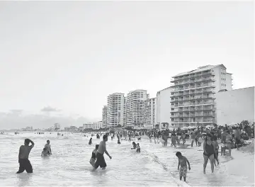  ??  ?? Beachgoers wade on the beach in Cancun, Mexico, on Apr 4, 2015.