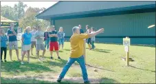  ?? Keith Bryant/The Weekly Vista ?? Disc golf pro Ray Moore, left, foreground, watches as George Osburn tries driving a disc at Branchwood’s first hole.