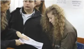  ?? (Ammar Awad/Reuters) ?? AHED TAMIMI looks at a document handed to her by lawyer, Gaby Lasky, at the military courtroom at Ofer Prison near Ramallah yesterday.