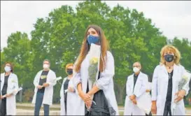  ?? AFP ?? Doctors prepare to lay flowers during a memorial for healthcare workers who lost their lives to the Covid-19 pandemic in Madrid, Spain.