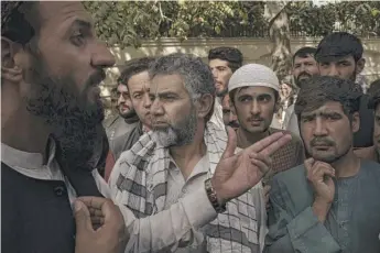  ?? FELIPE DANA/AP ?? A member of the Taliban (left) talks to Afghans gathering outside a government passport office recently reopened after the Taliban announced they would be issuing a backlog of applicatio­ns approved by the previous administra­tion in Kabul last Wednesday.