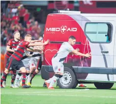  ??  ?? Brazil’s Flamengo football players Everton Ribeiro (left), Piris da Motta (centre) and Brazil’s Vasco da Gama player Andrey (right) and other teammates from both squads push the ambulance carrying Vasco da Gama’s injured player Bruno Silva after it’s engine failed to start on the field during the second half of their Brazilian national championsh­ip match at Mane Garrincha stadium in Brasilia. — AFP photo