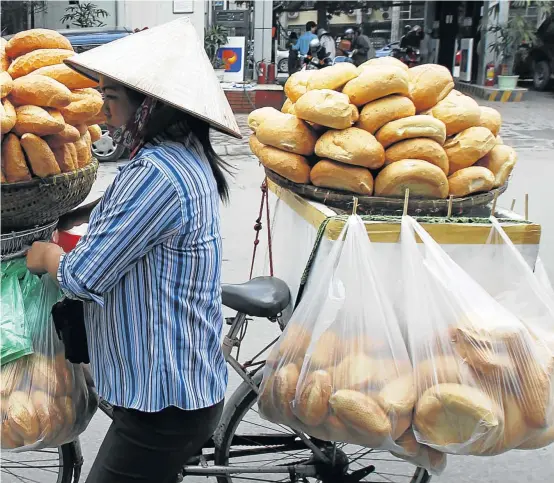  ??  ?? BANTING BANISHED: Transporti­ng the daily bread by bike down a Hanoi street
Pictures: REUTERS