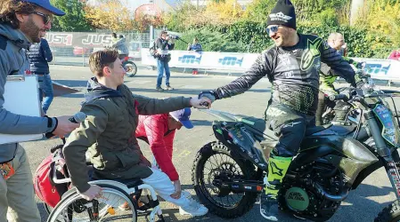  ?? In pista ?? Il campione di motocross Vanni Oddera prende la mano a un ragazzo in carrozzina: presto salirà sulla sua moto e proverà il brivido del cross
