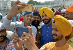  ?? — AFP ?? Punjab minister Navjot Singh Sidhu (centre) poses for ‘selfies’ with supporters at the Golden Temple in Amritsar on Wednesday.