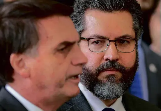  ??  ?? O novo chanceler brasileiro, Ernesto Araújo, observa o presidente eleito, Jair Bolsonaro, durante entrevista coletiva em Brasília nesta quarta (14)