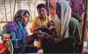  ??  ?? A Rohingya woman being taught how to use the safety alarm issued by the Moonlight Developmen­t Society at a clinic in the Chakmarkul refugee camp in Cox’s Bazar, Bangladesh, recently.