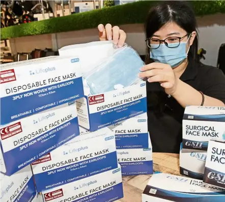  ?? — CHAN BOON KAI/The Star ?? Life savers: Pharmacy worker Teoh Hui Min inspecting a shipment of face masks at Island Glades in George Town, Penang.