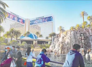  ?? Rachel Aston Las Vegas Review-journal @rookie__rae ?? Visitors hang out in front of The Mirage on Monday. The property will open the new year by shutting down totally from Mondays through Thursdays because of a drop in business and the COVID-19 restrictio­ns on group gatherings.