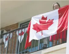  ??  ?? Cheryl Cartier holds a Canadian flag at Windsor’s Solidarity Towers July 1.