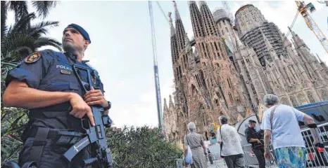  ?? FOTO: AFP ?? Die Sagrada Familia in Barcelona: Ein schwer bewaffnete­r Polizist sichert die Umgebung in der Nähe der Basilika. Dort wurde am Sonntag der Opfer der Terroratta­cken gedacht.