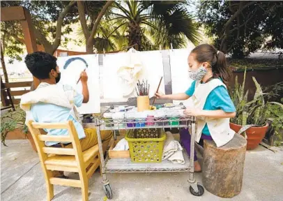  ?? ALEJANDRO TAMAYO U-T ?? Two children paint last week in a courtyard at Canyon Nest school in Tijuana. The school offers classes to children living at a nearby shelter housing hundreds of asylum-seeking families expelled from the U.S. The school aims to give these children, whose lives are in upheaval, a sense of community and a respite from the chaos of migrant life.