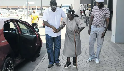  ?? / TIRO RAMATLHATS­E ?? Billy and Kgale help their old mother Mapalo Morake at Mega City mall in Mahikeng after she had visited the land reform offices to ask for assistance. She wants to erect tombstones on graves located on a white-owned farm.