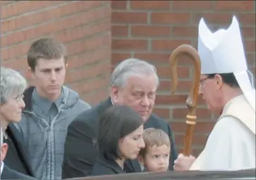  ??  ?? Left, Rev. Mansell speaks with family members of Thomas A. Budrejko, including his mother, Mary, left; father, Donald, center; wife, Diana, foreground; and 2-year-old son, Andrew, outside the church.