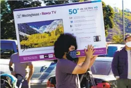  ??  ?? Christian Govea carries a spontaneou­s purchase back to his car on Friday from Best Buy — a 50-inch 4K television.