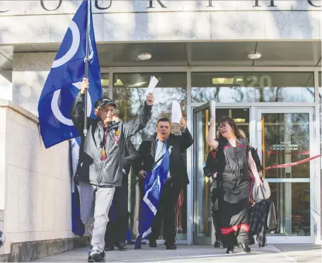  ?? LIAM RICHARDS ?? Jim Durocher, president of A La Baie Metis Local 21, left, and Ron Quintal, president of the Fort Mckay Metis Nation, carry flags as they lead a group of supporters out of the Court of Queens Bench in Saskatoon on Wednesday after filing a huge land claim against the federal government.