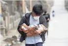  ?? AARON FAVILA/AP ?? An animal volunteer carries a dog he rescued from deserted homes near Taal volcano Wednesday.