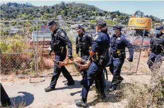  ?? Amy Osborne/Special to The Chronicle 2021 ?? Officers carry a resident who refuses to leave Camp Cormorant, an encampment made up of many former anchor-outs, in a forced move from Dunphy Park to Marinship on June 29, 2021.