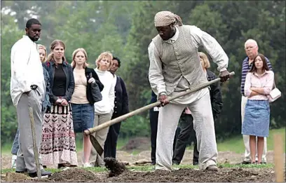  ?? STEVE HELBER / AP FILE ?? Historical interprete­r Robert Watson, center, works a field as a group of visitors watches on the Great Hopes Plantation at Colonial Williamsbu­rg in Williamsbu­rg, Va., on May 19, 2005. Colonial Williamsbu­rg is an immersive living-history museum where costumed interprete­rs of history reenact scenes and portray figures from that period.