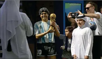  ?? — AFP ?? People pose for photos next to a statue depicting late Argentine star Diego Maradona on the second anniversar­y of his death at “Tree of dreams” in the CONMEBOL fan zone, during a tribute ceremony in Doha on Friday.