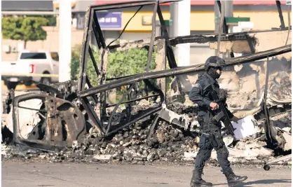  ?? AFP ?? VIOLENCIA. Un policía pasa junto a un vehículo quemado en octubre de 2019, en el llamado “Culiacanaz­o”. Hoy enfrentan otra crisis en el Estado.