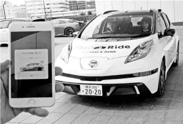  ??  ?? A self-driving vehicle is pictured next to a mobile phone with an app to reserve the service, during its media preview in Yokohama, Japan, February 21, 2018. — Reuters pic