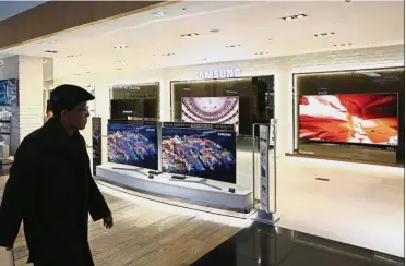  ?? – Bloomberg ?? Supply deal: A man walks past Samsung Electronic­s Co SUHD television­s displayed at the company’s D’light flagship store in Seoul. LG will supply as many as 3 million LCD panels to Samsung this year.