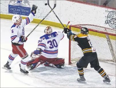  ?? JASON SIMMONDS/JOURNAL PIONEER ?? Summerside D. Alex MacDonald Ford Western Capitals defenceman Brodie MacMillan and the Campbellto­n Tigers’ Drew Toner look to knock the puck out of the air behind Caps goaltender Dominik Tmej during first-period action Thursday night. The Tigers...