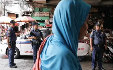  ?? PICTURE: AP ?? ARMED PRESENCE: A woman passes by policemen at a checkpoint in downtown Manila, Philippine­s yesterday as the Philippine National Police is placed on full alert following the declaratio­n of martial law in Mindanao.