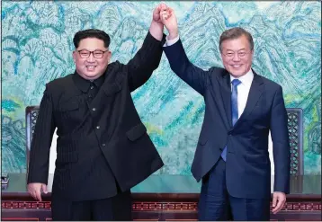  ?? (File Photo/AP/Pool/Korea Summit Press) ?? Kim (left) and South Korean President Moon Jae-in raise their hands April 27, 2018, after signing a joint statement at the border village of Panmunjom in the Demilitari­zed Zone, South Korea.