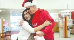  ??  ?? Bank of America’s Alejandra Ordaz hugs Bob Whittaker as the Running Santas from Lodi High make the rounds at Downtown businesses.