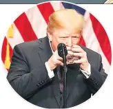  ??  ?? TAKING A TOT Trump holds glass like child