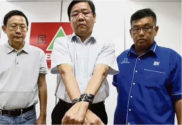  ??  ?? My hands are tied: Teng (centre), flanked by Lee (left) and Tan, mocking Lim’s move to sue him by taping his hands with a black masking tape during the press conference at the Gerakan headquarte­rs in George Town.