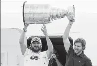  ?? AP PHOTO ?? Washington Capitals left wing Alex Ovechkin, left, of Russia, and center Nicklas Backstrom, of Sweden, right, hold up the Stanley Cup as the Capitols arrive at Dulles Internatio­nal Airport in Sterling, Va., Friday, the day after defeating the Vegas...