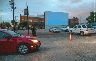  ??  ?? An usher directs a vehicle Tuesday at ChiTown Futbol on the first night of drive-in movies in its parking lot.