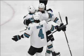  ?? AP PHOTO/TOM OLMSCHEID ?? San Jose Sharks’ Brent Burns, back, hugs Dylan Gambrell as teammate Brenden Dillon (4) joins the celebratio­n after Gambrell scores a goal against the Minnesota Wild in the third period of an NHL hockey game, on Saturday in St. Paul, Minn.