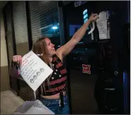  ?? (The New York Times/Matthew Busch) ?? Bartender Amber Jowers takes down mask-requiremen­t notices early Wednesday at Barflys in San Antonio, as orders requiring masks and occupancy limits on restaurant­s and other businesses were lifted across Texas. Some medical experts called the relaxed rules premature.