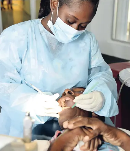  ?? IAN ALLEN/PHOTOGRAPH­ER ?? Kimberly Oliver final-year student at the University of Technology’s College of Oral Health Science, treats Gladstone Cummings at the recent back-to-school medical and dental health fair held at the college.