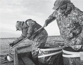  ?? PAUL A. SMITH ?? Bruce Urben, right, of Green Bay and Pat Gregory of Bloomingto­n, Illinois, lay out a line of decoys on the waters of Green Bay near Oconto during the eighth annual Delta Waterfowl Decoy Hunt.