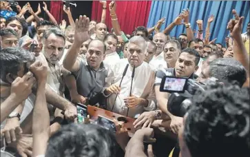  ?? Isharas Kodikara AFP/Getty Images ?? RANIL WICKREMESI­NGHE, center, was fired Saturday as prime minister; he called the move a constituti­onal coup. The new premier, Mahinda Rajapaksa, was president for a decade and accused of war crimes.