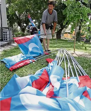  ??  ?? Purpose fulfilled: A party helper removing Pakatan flags in Jalan Sungai Kelian, Tanjong Bunga.