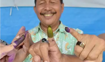  ??  ?? Indonesian men show their inked fingers after casting their ballots during regional elections in Tangerang, Banten. — AFP photo