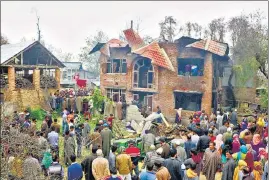  ?? PTI ?? Locals stand near a damaged building after a clash between terrorists and army personnel, in Anantnag district on Sunday. An Army spokespers­on said the two militants killed here were behind the killing of Havaldar Mohd Saleem Akhoon of Territoria­l Army on Friday