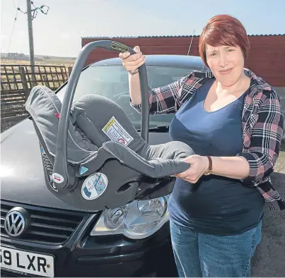  ??  ?? TRAVELLING GEAR: Susanne Robertson with car seat she will have to use for her baby on her 120-mile journey